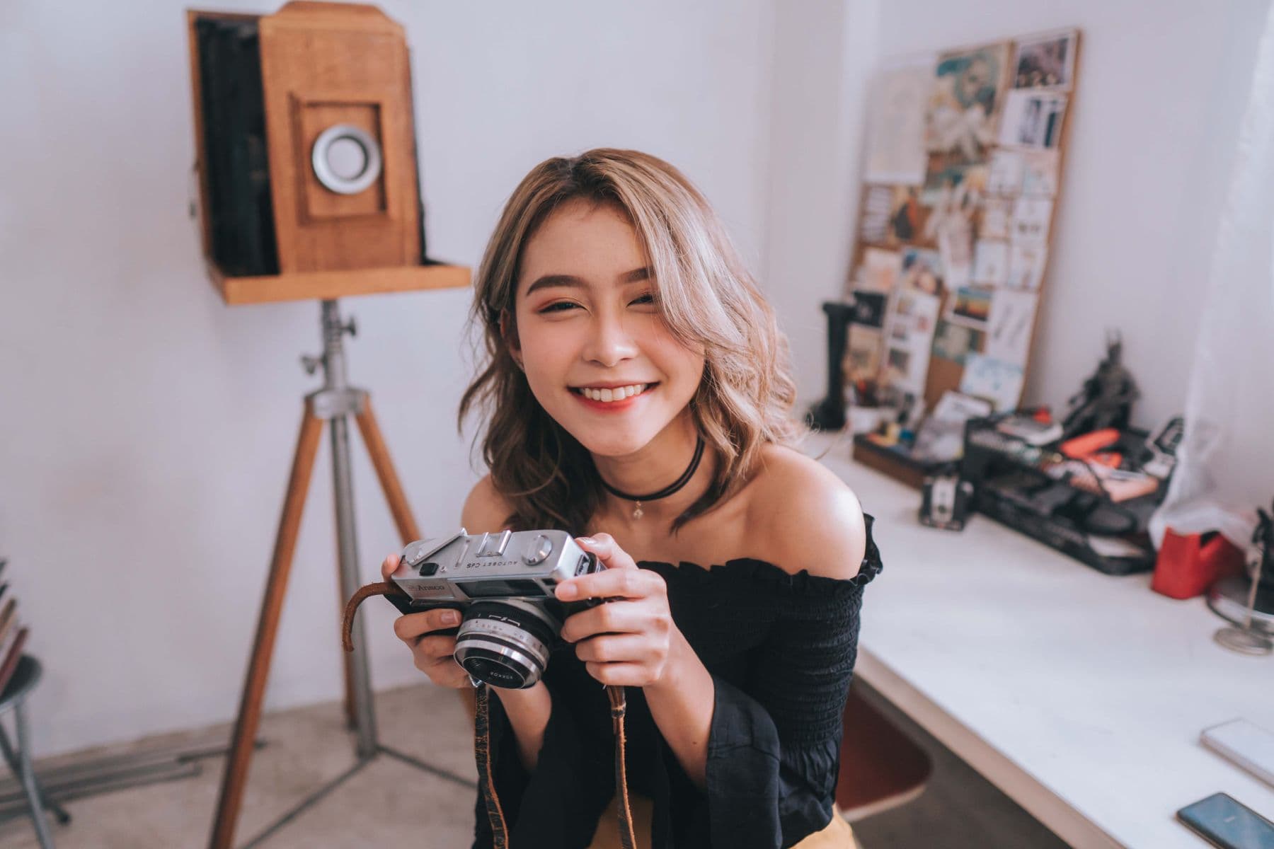 A photographer holding a rangefinder camera inside a working studio.