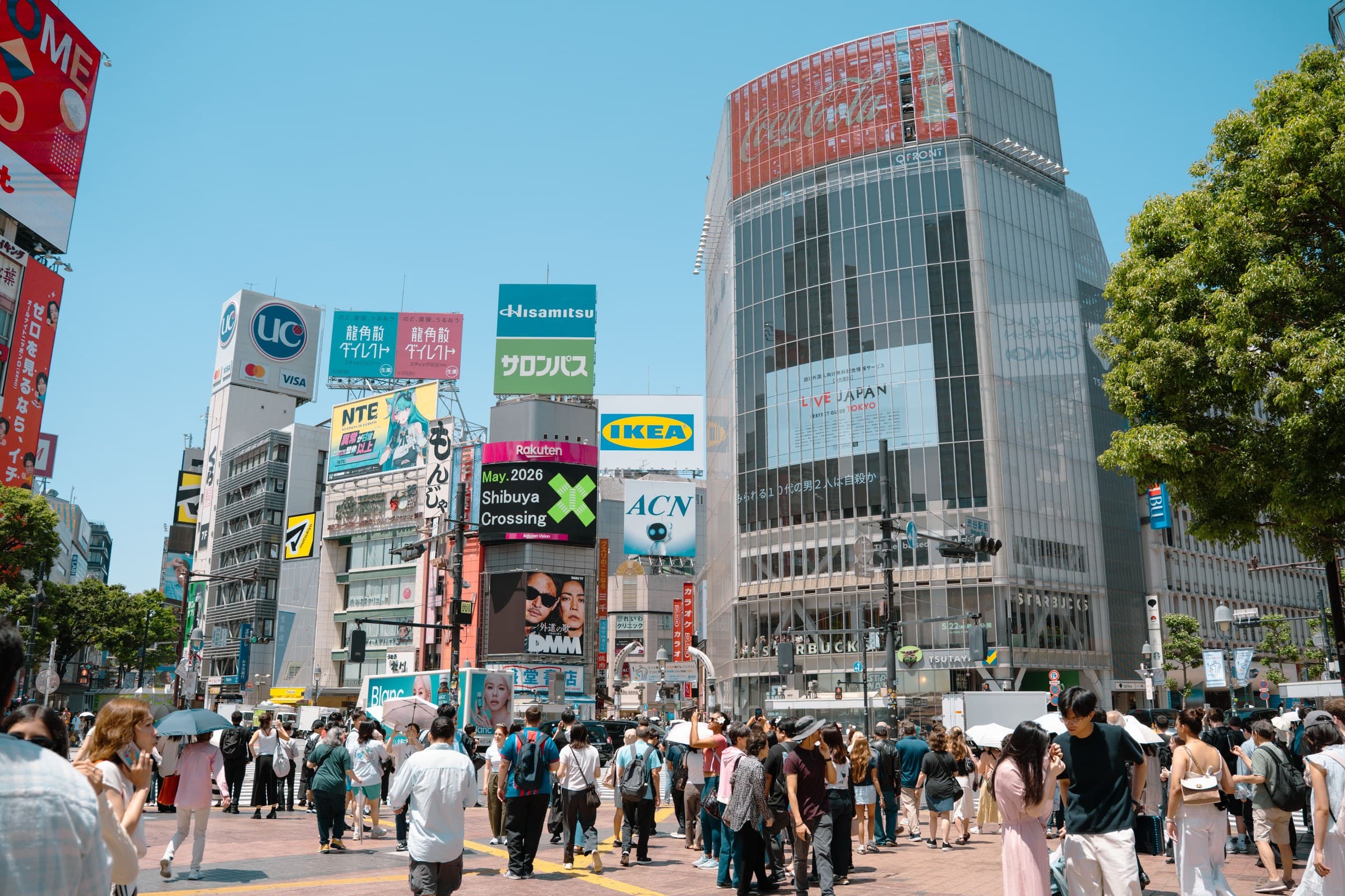 A city crossing surrounded by large digital advertising screens and billboards.