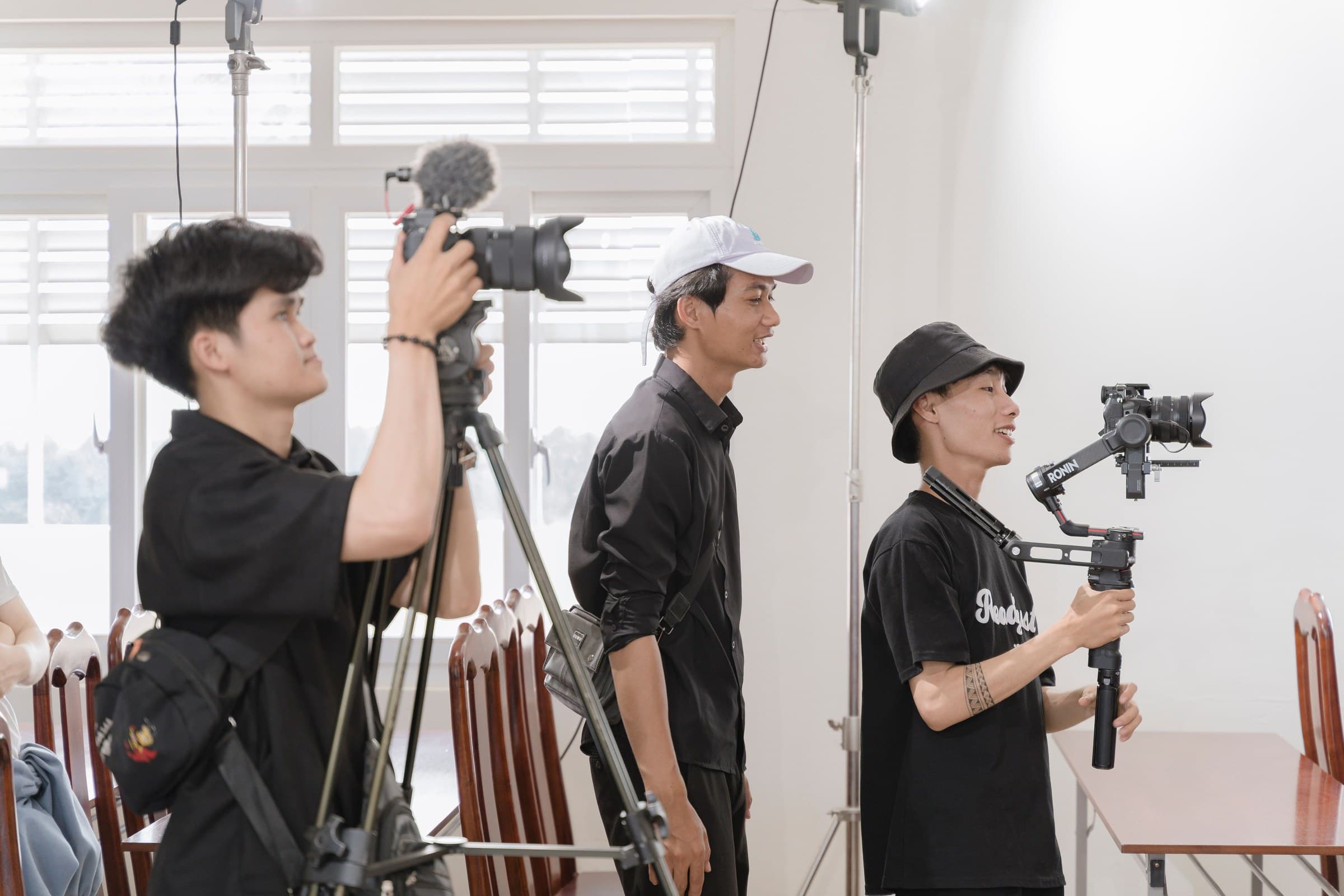 A three-person camera crew on set with a tripod camera and a gimbal operator.